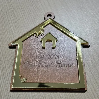 House-shaped new home ornament with a gold mirror acrylic frame on cherry plywood, engraved with Est. 2024 and Our First Home