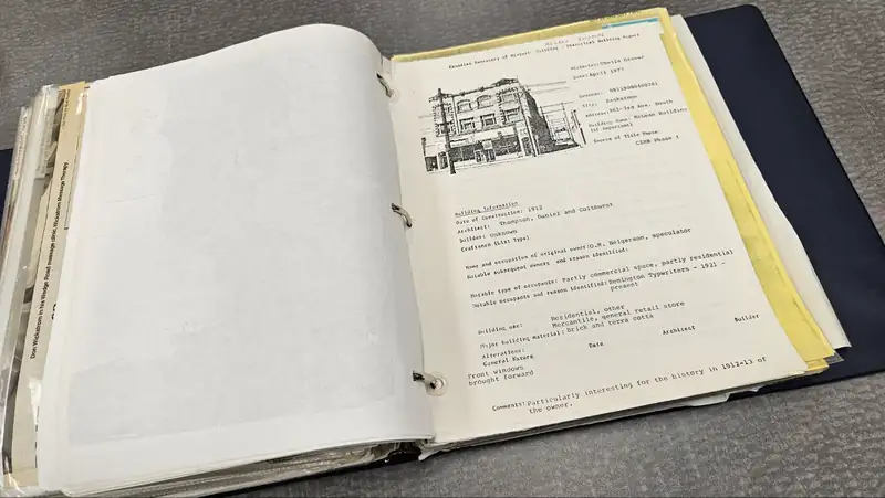 An open binder of historical building reports with a pen drawing of a brick storefront