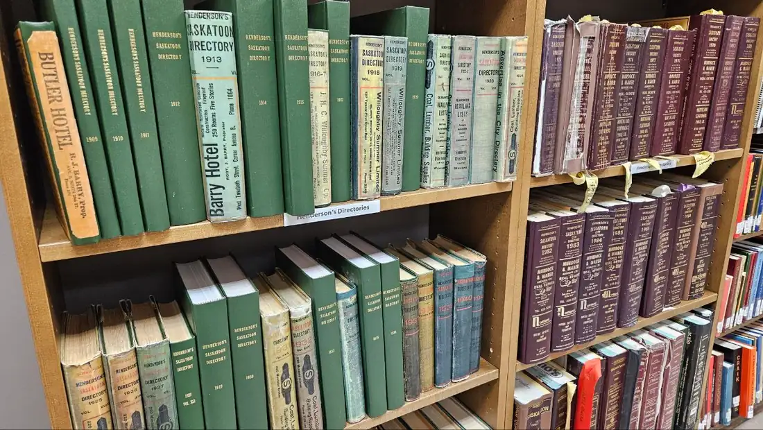 Library shelves of green and maroon bound city directories from the early 1900s onward