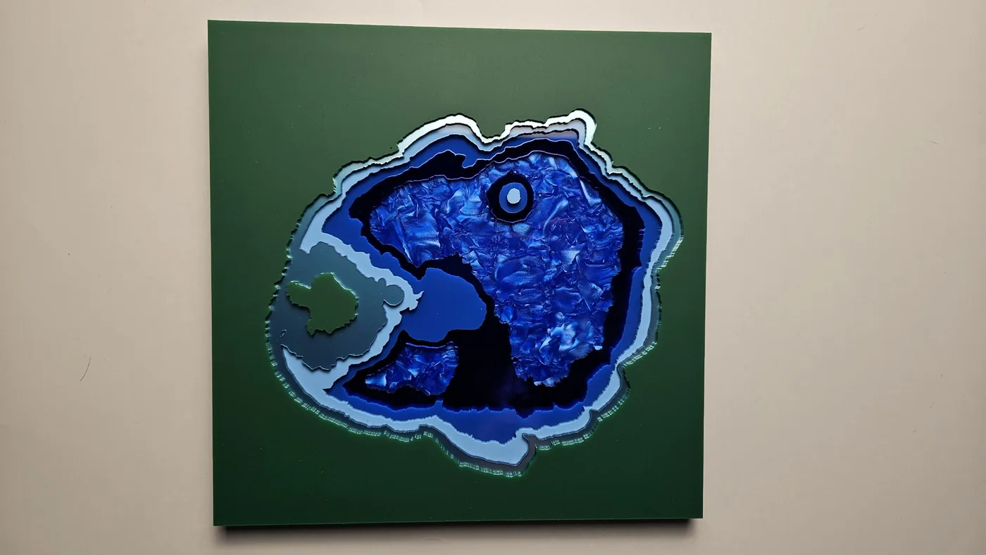 A laser-cut Crater Lake map with layered blue depth bands on a green panel