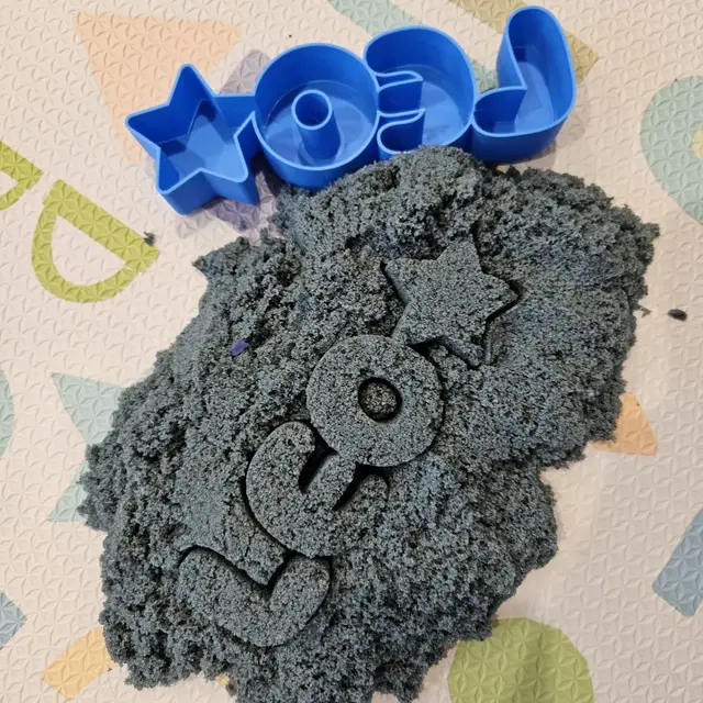 3D printed name cutter used in kinetic sand showing letters pressed into the sand