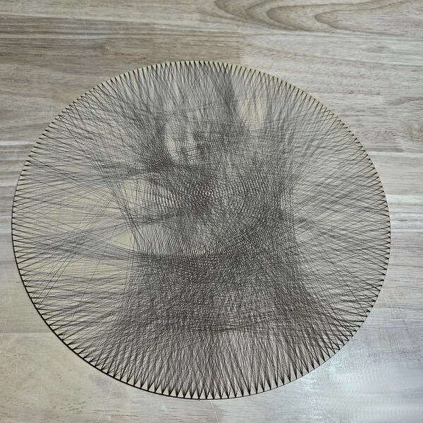 Round maple plywood disc with a portrait threaded in dark string between hundreds of edge pegs